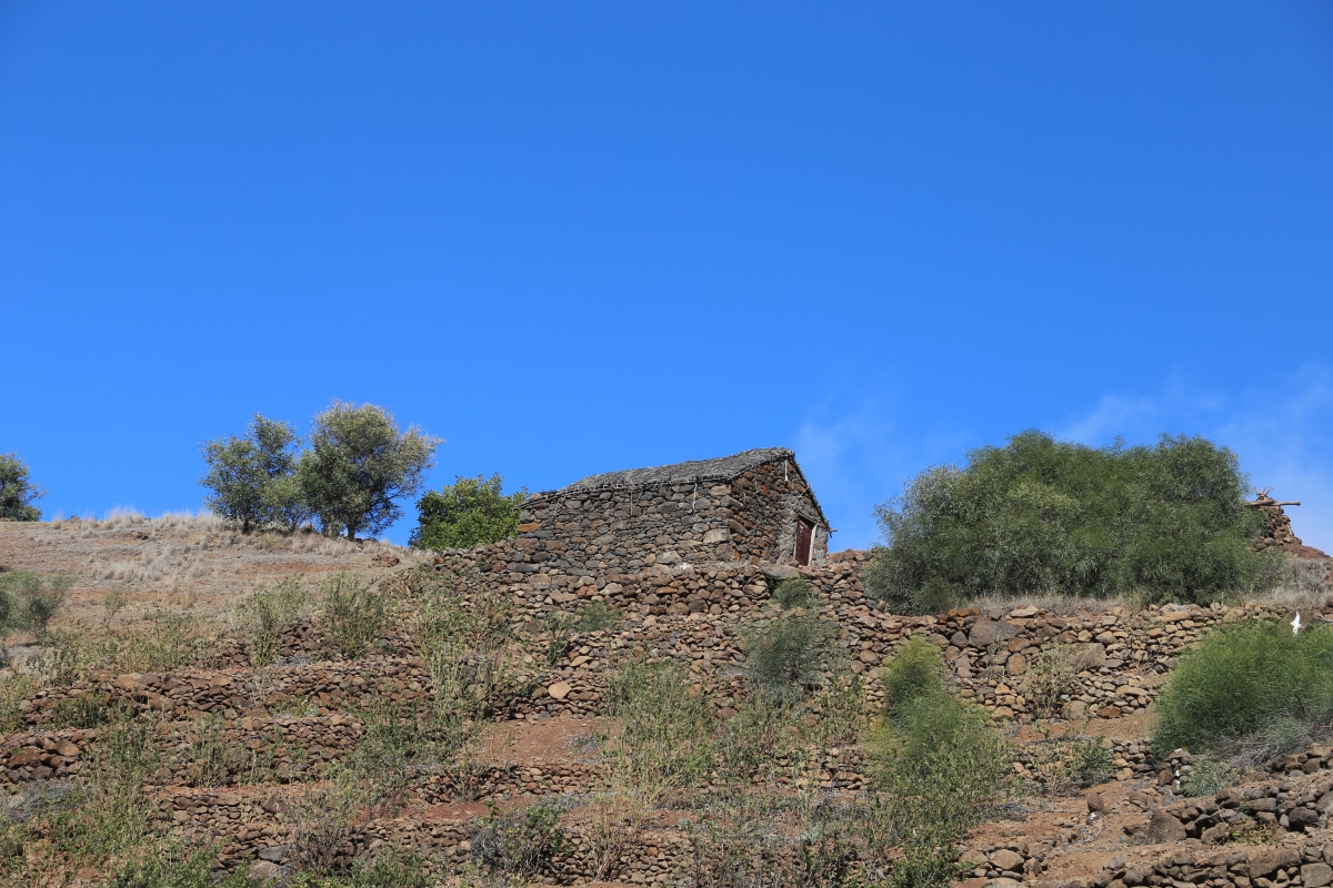 Terrassierte Felder mit traditionellem Haus in karger Landschaft, Wanderung von Lagoa nach Caibros